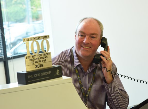 Smiling male CHS customer service advisor speaking to a customer on the phone with Times 100 best for award