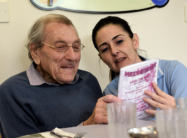 Cambridge Care home assistant showing an elderly resident the menu options at mealtime