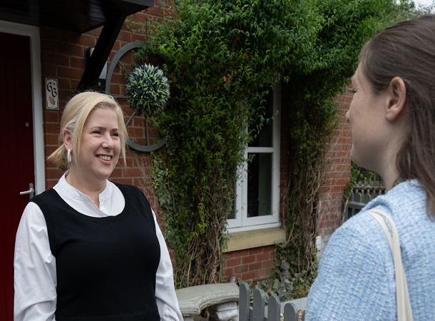 CHS white female tenant outside front door talking to staff