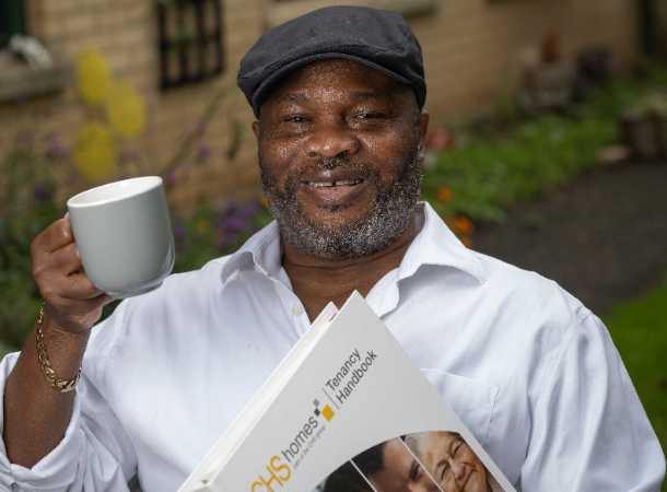 Smiling black man holding the CHS tenancy handbook